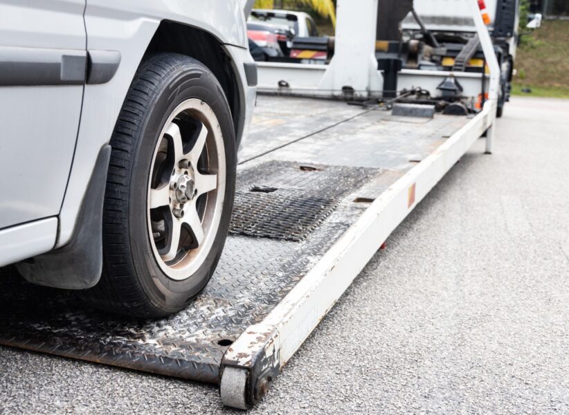 Cable attached to broken down car being pulled onto tow truck Cable attached to broken down car being pulled onto flatbed tow truck